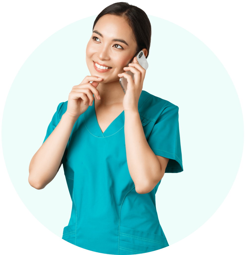 An Image of a women in scrubs, smiling and on the her cell phone.